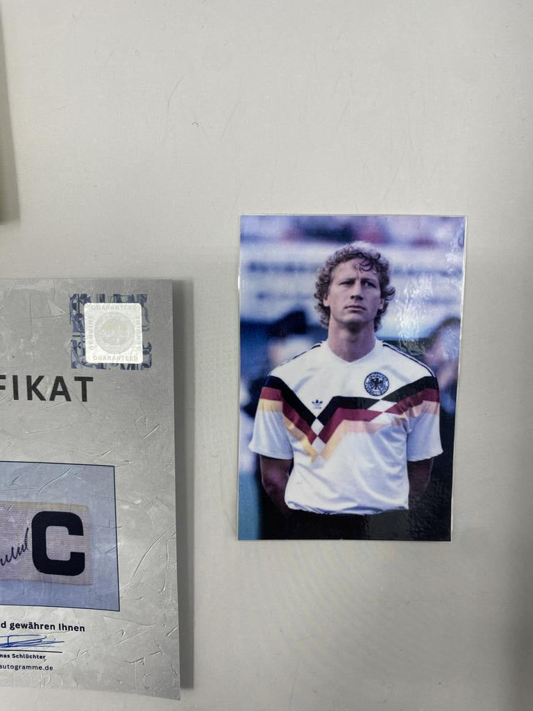 Captain's armband signed by Guido Buchwald in a Germany Football autograph frame