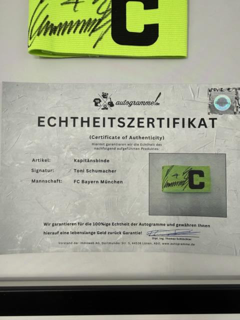 Kapitänsbinde Toni Schumacher signiert im Rahmen FC Bayern München Fußball Autogramm
