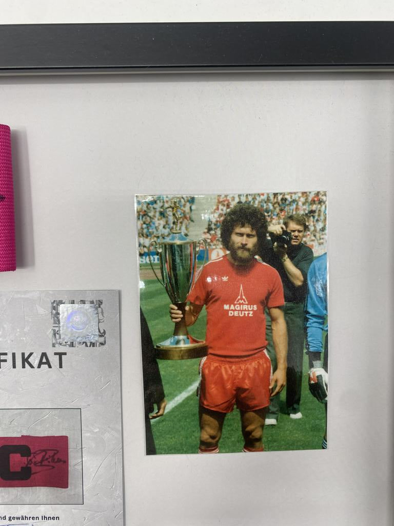 Brazalete de capitán firmado por Paul Breitner en un marco de autógrafos del Bayern de Múnich.