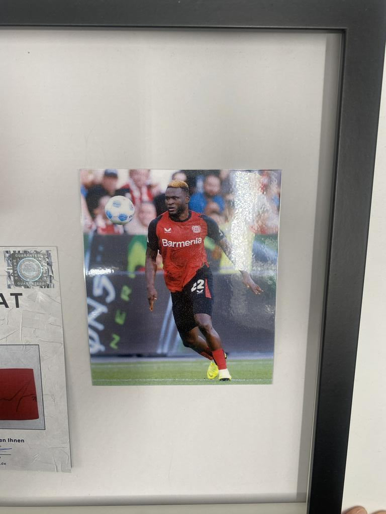 Kapitänsbinde Victor Boniface signiert im Rahmen Bayer Leverkusen Autogramm