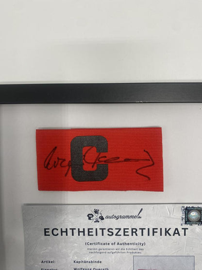 Kapitänsbinde Wolfgang Overath signiert im Rahmen 1. FC Köln Autogramm
