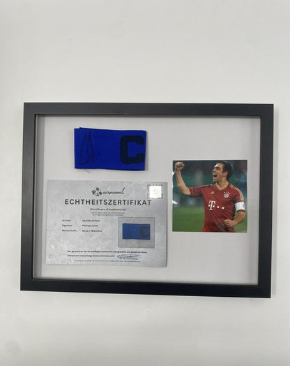 Brazalete de capitán firmado por Philipp Lahm en un marco de autógrafos del Bayern de Múnich.