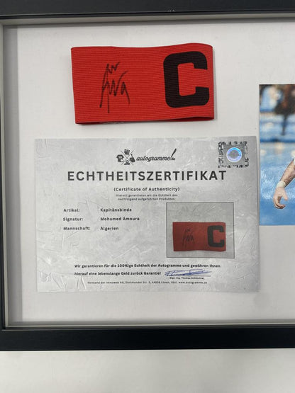 Brazalete de capitán firmado por Mohamed Amoura enmarcado, Argelia. Certificado de Autenticidad de Autógrafos.