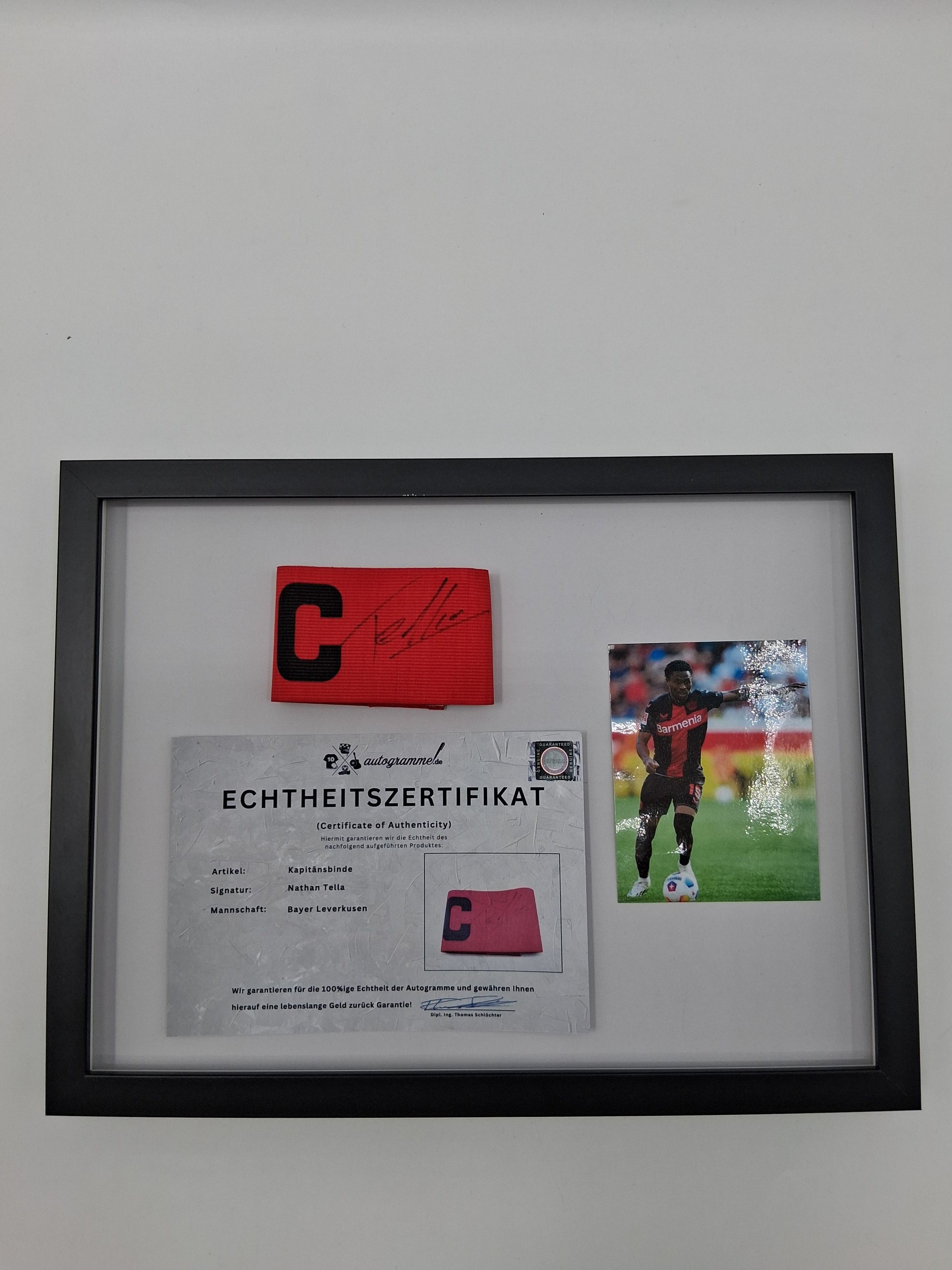 Kapitänsbinde Nathan Tella signiert im Rahmen Bayer Leverkusen Autogramm