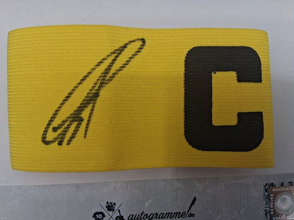 Brazalete de capitán firmado por Karim Adeyemi en un marco con certificado de autenticidad del Borussia Dortmund.
