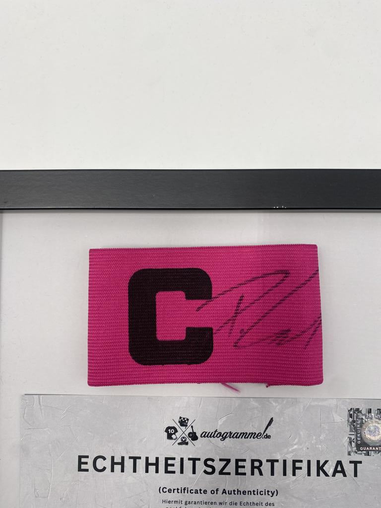 Brazalete de capitán firmado por Deniz Undav en un marco de autógrafos del VfB Stuttgart.