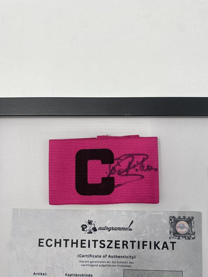 Brazalete de capitán firmado por Paul Breitner en un marco de autógrafos del Bayern de Múnich.